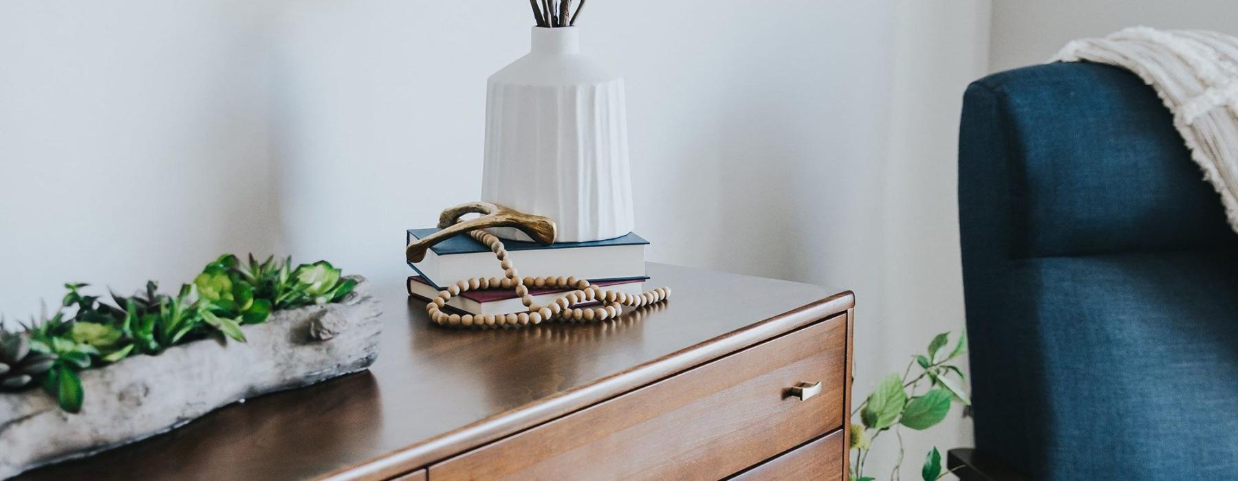 a dresser with a vase of plants on top